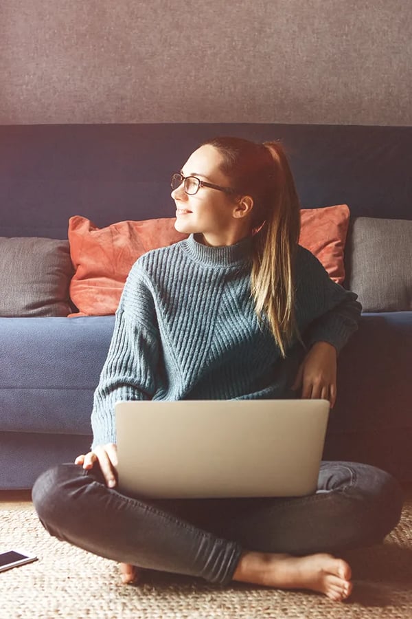 Henkilö istuu lattialla tietokone sylissään