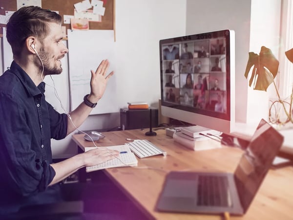 henkilö vilkuttaa tietokoneen ruudun kautta muille henkilöille